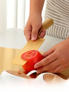 Close-up of golden stainless steel chef knife slicing through a fresh tomato
