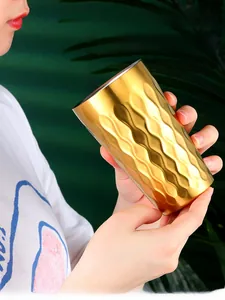 Gros plan du gobelet doré en acier inoxydable montrant la texture ondulée et isolée