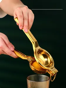 Manual stainless steel lemon squeezer with golden finish shown pressing juice into a glass