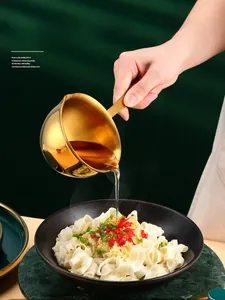 Action shot of pouring hot oil from a gold stainless steel mini pan onto noodles
