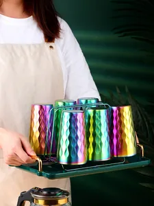 Gobelets en acier inoxydable arc-en-ciel avec texture sur égouttoir métal et plateau vert