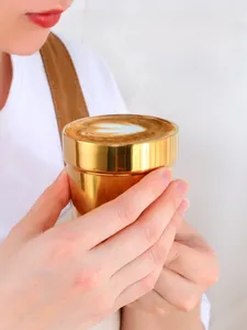 Model holding a double-walled golden stainless steel Korean tea cup for insulation