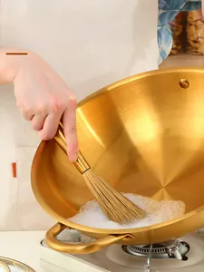 Golden 18/8 stainless steel pot brush showing dense wire bristles cleaning a pan with foam