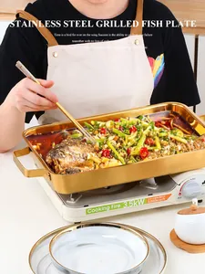 Rectangular gold stainless steel fish grill pan with handles used on a portable stove
