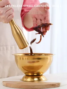 Action shot of red chili peppers falling into a premium gold stainless steel mortar and pestle