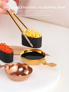 Close-up of gold and rose gold stainless steel seasoning dishes with handles on marble