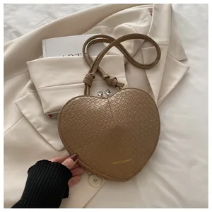 Detail of camel heart-shaped crossbody bag with crocodile texture and double zippers