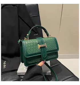 Close-up of dark green woven texture bag with gold H-shaped clasp and handle