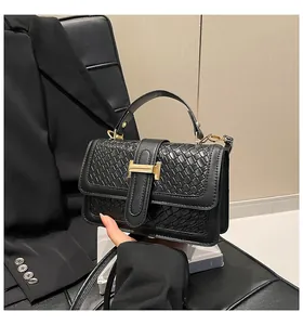 Close-up of black woven texture handbag with golden H-shaped buckle and strap
