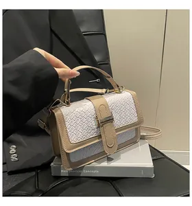 Detail of contrast weave texture and metal buckle on cream faux leather handbag