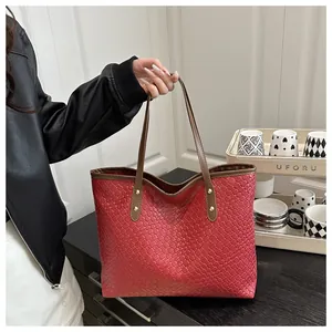 Detail view of burgundy woven tote bag with brown leather straps and gold rivets