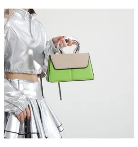 Detail of color-block bag featuring a green base, woven flap, and silver metallic handle