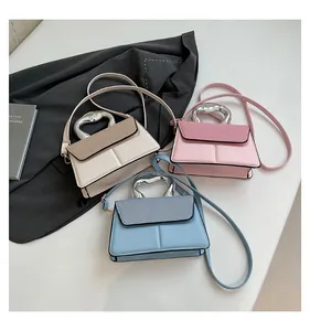 Three mini crossbody bags in beige, pink, and blue with heart-shaped metal handles