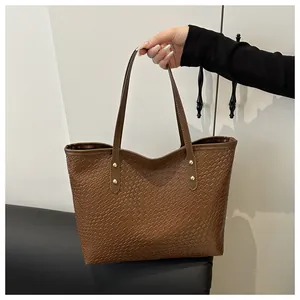 Close-up of brown woven texture tote bag with golden metal rivets and spacious design