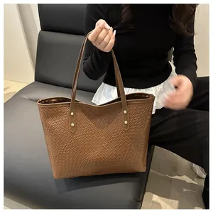 Detailed view of dark brown woven texture tote bag with golden rivets and slim straps