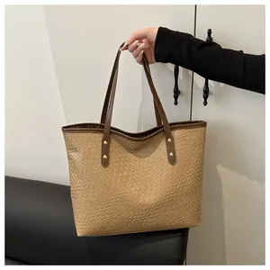 Detail shot of large khaki tote bag featuring embossed crocodile texture and gold metal studs