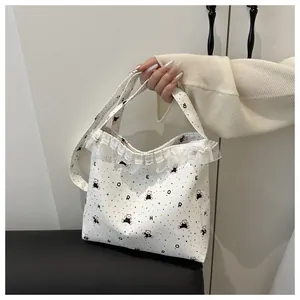 Détail du sac cabas en dentelle blanche avec ours colorés et bordure en organza