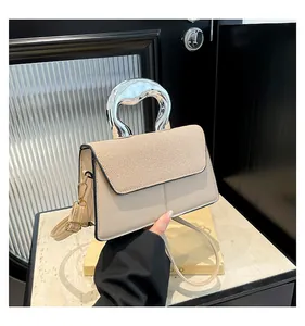 Detail of elegant beige handbag with a silver geometric hollow metal handle and leather strap