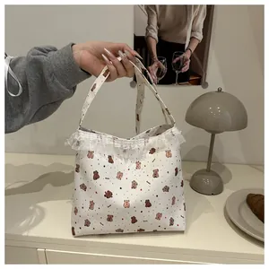 Détail du sac cabas en toile blanche avec motifs d'ours mignons et bordure en dentelle