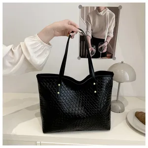 Close-up of black woven tote bag featuring gold rivet hardware and leather texture