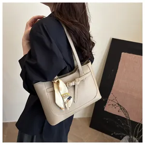 Détail d'un cabas en cuir beige avec boucle décorative et accessoire élégant en foulard de soie