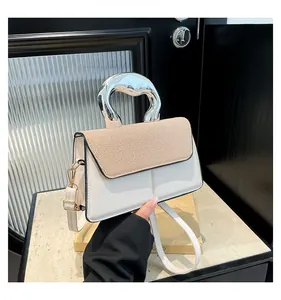 Detail of modern silver mirror handle and contrasting texture on small square bag