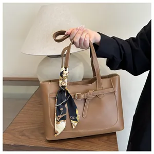 Détail d'un sac cabas marron avec boucle décorative et poignée en foulard de soie