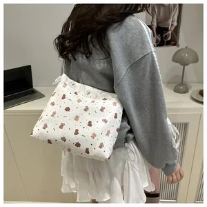 Détail d'un sac cabas en toile blanche avec motifs ours et bordure en dentelle fine