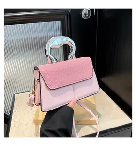 Detail of pink crossbody bag showing silver metal handle and striped leather flap texture