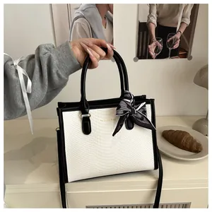 Detail of white snake pattern handbag with contrast black trim and silk scarf handle