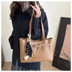 Détail d'un sac cabas marron avec texture cuir fine et accessoire de foulard en soie décoratif