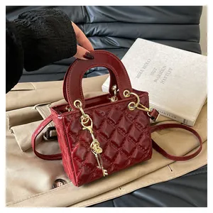 Dettaglio della borsa in pelle bordeaux trapuntata con ciondolo a chiave dorata
