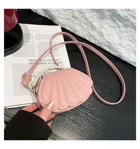 Gros plan sur un sac coquillage rose avec anse en perles et finitions dorées chics