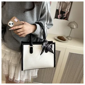 Detail of snake skin texture and silk scarf bow on black and white crossbody handbag
