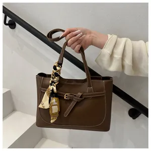 Détail du sac cabas marron foncé avec coutures blanches contrastées et foulard en soie décoratif