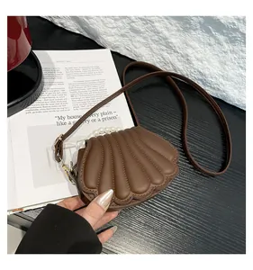 Gros plan du sac marron en forme de coquillage avec anse en perles et cuir lisse