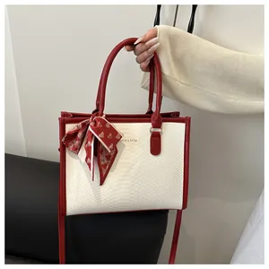 Detail of red and white contrast handbag with snake pattern texture and silk scarf bow