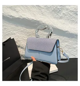 Detail of light blue crossbody bag with metallic silver handle and contrast texture