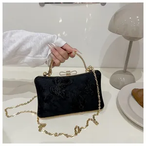 Close-up of black velvet evening bag featuring intricate butterfly embroidery and a gold handle