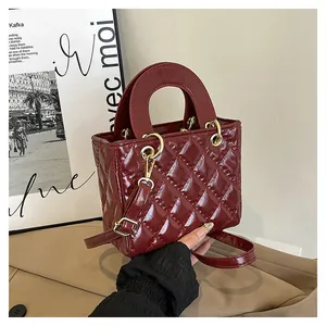 Dettaglio della borsa in vernice trapuntata rosso vino con finitura lucida e finiture oro