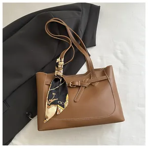 Détail du sac cabas caramel avec surpiqûres contrastées et un foulard en soie à chaînes