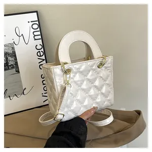 Dettagli della texture trapuntata e finiture dorate sulla borsa a mano bianca