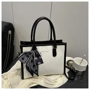 Detailed view of snake-embossed contrast handbag with decorative printed silk scarf