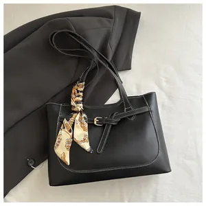 Détail du sac cabas en cuir noir avec surpiqûres blanches et foulard en soie imprimé décoratif