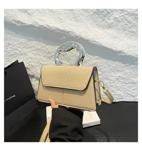 Detail of crossbody bag with silver metal handle and straw woven textured flap