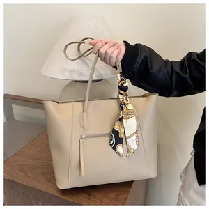 Detail of beige faux leather tote bag with functional zipper pocket and decorative silk scarf