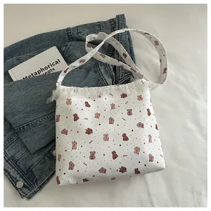 Détail du sac cabas en toile blanche avec bordure en dentelle et motifs d'animaux