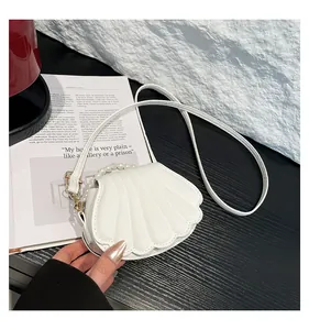 Détail du sac à main blanc en forme de coquillage avec poignée perle et métal doré