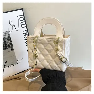 Dettaglio borsa trapuntata beige in pelle con ciondolo a chiave dorata e manico rigido