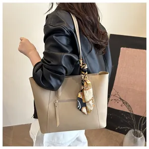 Close-up of khaki leather tote bag with elegant floral silk scarf on the handle